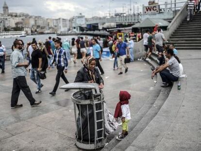 Un ni&ntilde;o sirio refugiado mira a su madre recoger basura en Estambul.