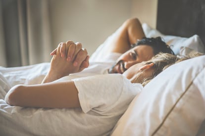 Hispanic couple holding hands in bed