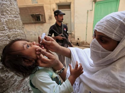 Mulher vacina menina contra a pólio em Peshawar (Paquistão).