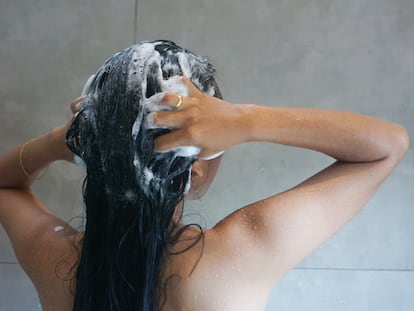 Chica de espaldas lavándose el pelo.