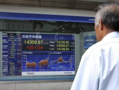 Un viandante pasa delante de una pantalla que muestra el índice Nikkei. EFE/Archivo