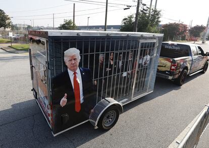 Un seguidor del expresidente estadounidense Donald Trump maneja un remolque que muestra imágenes de líderes demócratas en una celda. 
