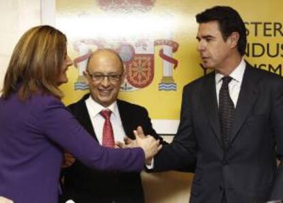 El ministro de Industria, Energía y Turismo, José Manuel Soria (d), y la ministra de Empleo, Fátima Báñez (i), se saludan en presencia del ministro de Hacienda, Cristóbal Montoro (c), durante el acto de toma posesión del nuevo secretario de Estado de Energía, Alberto Nadal, esta mañana en el Ministerio de Industria.