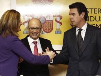 El ministro de Industria, Energía y Turismo, José Manuel Soria (d), y la ministra de Empleo, Fátima Báñez (i), se saludan en presencia del ministro de Hacienda, Cristóbal Montoro (c), durante el acto de toma posesión del nuevo secretario de Estado de Energía, Alberto Nadal, esta mañana en el Ministerio de Industria.