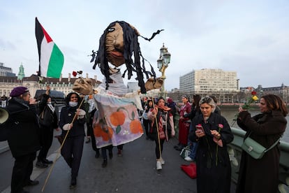 Varias manifestantes llevan una marioneta, a su paso por el Puente de Westminster, en Londres, por el Día Internacional de la Mujer, este viernes.