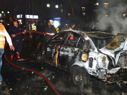 Bomberos tratan de apagar un coche quemado por la explosi&oacute;n.