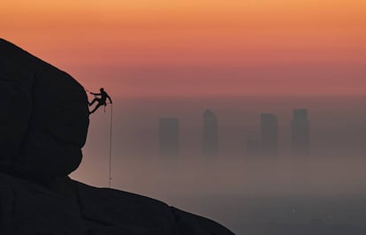 El bombero Antonio Marcos escala con las Cuatro Torres de fondo. Pincha sobre la imagen para ver más fotos de este 'skyline'.