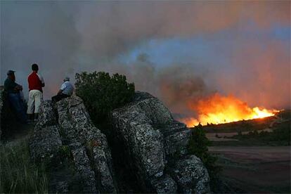 Unas personas miran el fuego desde una loma cerca de Santa Maria del Espino, en Guadalajara.