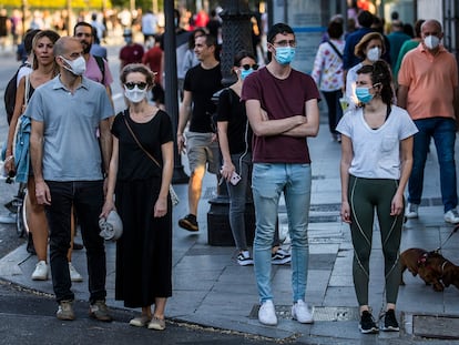Varias personas esperan en un semáforo en la calle Bailen de Madrid.