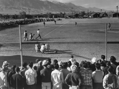UNITED STATES - CIRCA 1943:  Japanese Americans observe an amateur baseball game in progress; one-story buildings and mountains in the background. Ansel Easton Adams (1902  1984) was an American photographer, best known for his black-and-white photographs of the American West. During part of his career, he was hired by the US Government to record life in the West.  (Photo by Buyenlarge/Getty Images)