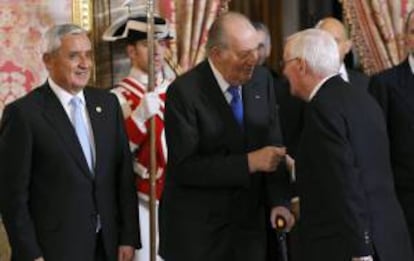 El Rey Juan Carlos saluda al director del Instituto Cervantes, Víctor García de la Concha (d), en presencia del presidente de Guatemala, Otto Pérez Molina (i), durante el almuerzo que los Reyes han ofrecido al mandatario guatemalteco y su esposa, Rosa Leal, hoy en el Palacio Real de Madrid.