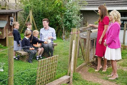 Kate Middleton y Jill  Biden conversan con un grupo de niños mientras estos alimentan a los conejos. 