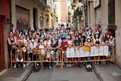 Un grupo de personas asiste desde un callejón a la Ofrenda a la Virgen, este domingo.
