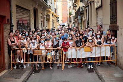 Un grupo de personas asiste desde un callejón a la Ofrenda a la Virgen, este domingo.