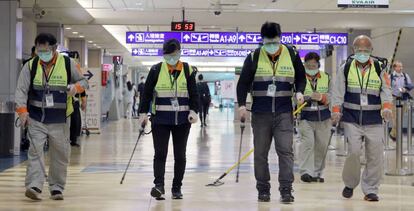 Trabajadores con mascarillas del aeropuerto internacional de Taoyuan (Taiwan, China) desinfectan las instalaciones.