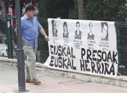 Un hombre pasa delante de un cartel con fotos de presos etarras en Bilbao.