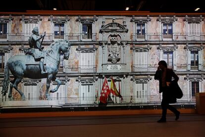 Una mujer pasa por delante de una pantalla del stand de Madrid.