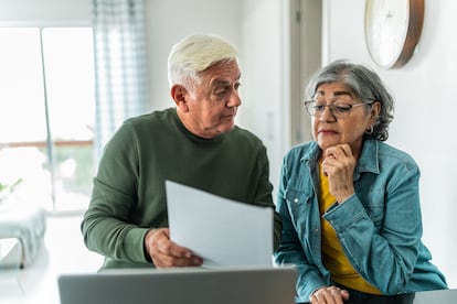 Una pareja de adultos mayores revisa sus finanzas en su hogar.