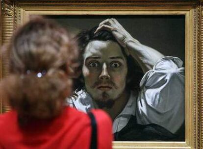 Una mujer contempla el autorretrato de Courbet, titulado <i>Le désésperé, </i>expuesto en el Grand Palais de París.