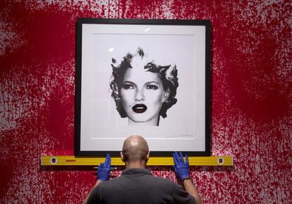 La sede londinense de Sotheby's acoge desde hoy la primera retrospectiva 'no autorizada' de la obra de Banksy. La subversión, encerrada entre las cuatro paredes de una galería enclavada en el exclusivo barrio de Mayfair, vale millones. El artista, obviamente, no ha acudido a la presentación. En la imagen, un empleado trabaja en una de las obras, que retrata a Kate Moss.