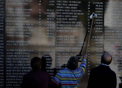Una mujer limpia el nombre de un familiar de un muro en memoria de los republicanos fallecidos durante la Guerra Civil, en el cementerio de San Salvador, de Oviedo (Asturias).