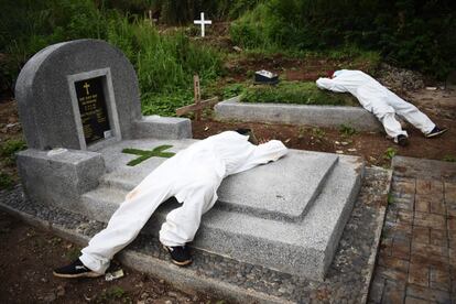 Dos sepultureros exhaustos descansan entre las tumbas de un cementerio destinado a víctimas de la covid-19 en Bandung, Indonesia.