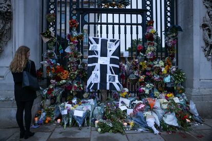 Una bandera de la Union Jack, en tonos negros y grises, desplegada a las puertas del palacio de Buckingham, en Londres, este viernes, junto a decenas de ramos de flores colocados por los ciudadanos en recuerdo de Isabel II.