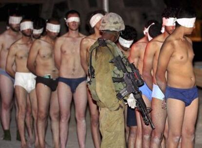 Un soldado israelí custodia a una fila de miembros del clan Helles llegados de Gaza, en el paso fronterizo de Nahal Oz
