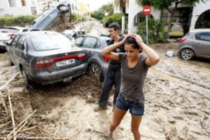 Vera (Almería). Dos personas caminan entre lodo y vehículos destrozados tras las fuertes lluvias caídas caídas el pasado viernes en Vera.