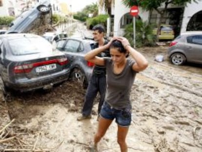 Vera (Almer&iacute;a). Dos personas caminan entre lodo y veh&iacute;culos destrozados tras las fuertes lluvias ca&iacute;das ca&iacute;das el pasado viernes en Vera.