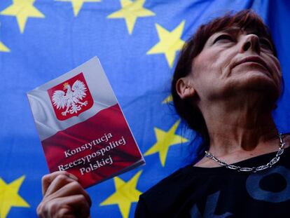 Una mujer con la Constitución de Polonia, bajo una bandera de la UE. 