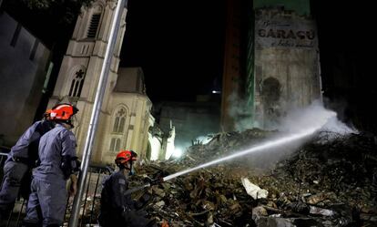 Bombeiros trabalham nos escombros do prédio desabado.