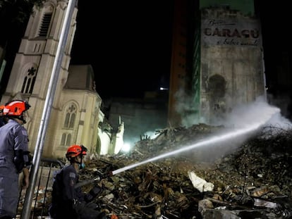 Bombeiros trabalham nos escombros do prédio desabado.