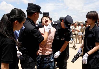 Oficiales de la policía china registran a un sospechoso de fraude antes de ser deportado a China, en el Aeropuerto Internacional de Phnom Penh (Camboya).