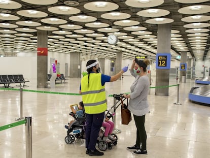 Una trabajadora toma la temperatura a una viajera en el aeropuerto de Madrid, en una imagen de 2020.