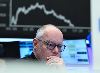 Un operador observa sus monitores en el parqué de la Bolsa de Fráncfort mientras el tablero con la curva del Dax muestra precios a la baja, este jueves.