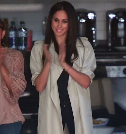Markle en su última aparición pública con camiseta y pantalón negro y un sencillo trench.