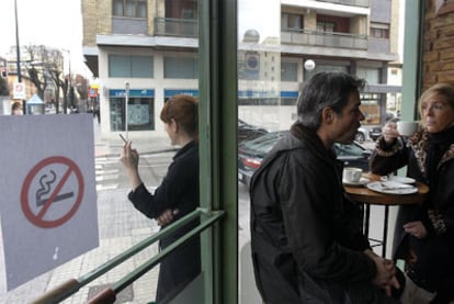 Una mujer fuma en la puerta de un establecimiento hostelero en Burgos el primer día de la entrada en vigor de la ley antitabaco.