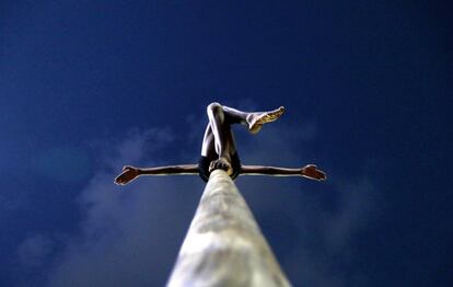 Un estudiante indio practica una postura mientras mantiene el equilibrio subido a un poste, durante un entrenamiento de Mallakhamba, en Mumbai (India).