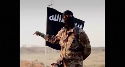 A masked man with an ISIS flag in the background.