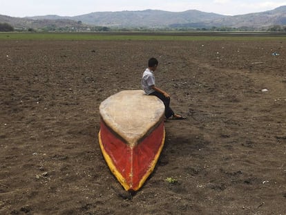 Un niño permanece sentado sobre un bote en el terreno seco sobre el que estuvo el lago Atescatempa.