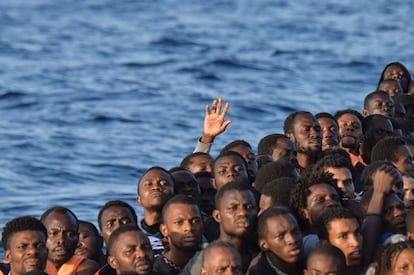 Migrantes y refugiados sentados en el bote de goma antes de ser rescatados por la ONG maltesa MOAS y la Cruz Roja italiana, en la costa libia. 