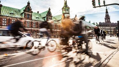 Ciclistas em Copenhague, com o edifício da Bolsa ao fundo