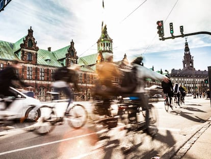 Ciclistas em Copenhague, com o edifício da Bolsa ao fundo