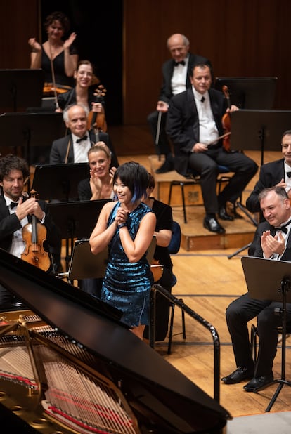 Yuja Wang agradece los aplausos de público y orquesta tras tocar una de las propinas. Al fondo, a la derecha, sentado, aún batuta en mano, Iván Fischer.