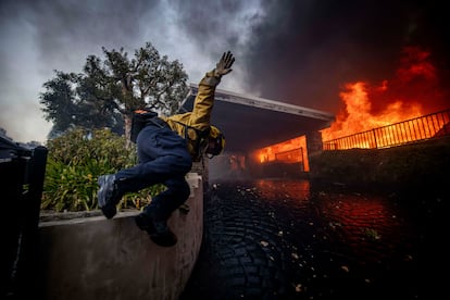 Un bombero salta sobre una valla en el vecindario de Palisades, el 7 de enero. 