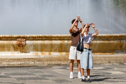 Dos turistas toman fotografías este lunes en el parque de María Luisa de Sevilla. 