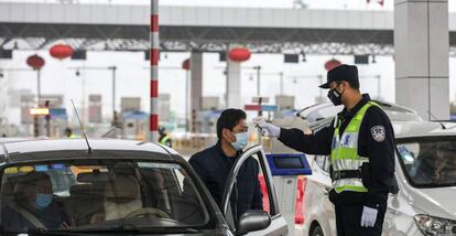 Un funcionario de policía toma la temperatura a un conductor en Wuhan.