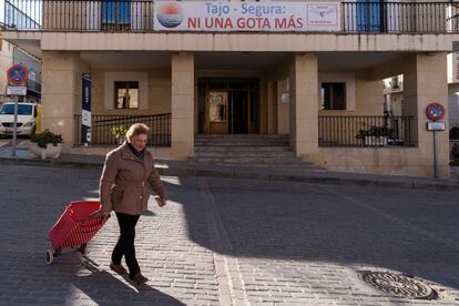 Una vecina de Sacedón pasa por delante del Ayuntamiento, en el que cuelga una pancarta en contra del trasvase Tajo-Segura.