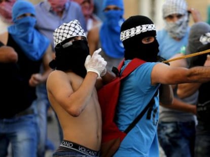 Palestino joga pedras contra a polícia israelense.